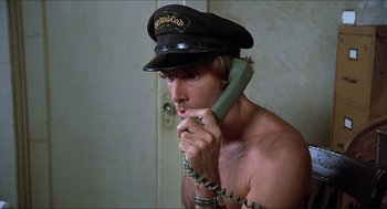 Movie still from “Family Plot” (1976), directed by Alfred Hitchcock – A man in a hat is talking on a phone; Close Up shot, Low angle