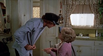 Movie still from “Family Plot” (1976), directed by Alfred Hitchcock – A man and a woman are talking in a room; Medium shot, Over the shoulder angle