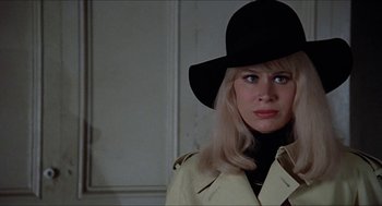 Movie still from “Family Plot” (1976), directed by Alfred Hitchcock – A woman wearing a black hat and a trench coat; Close Up shot, Low angle