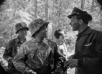 Movie still from “Fear and Desire” (1952), directed by Stanley Kubrick – A group of men standing next to each other in the woods; Medium shot, Over the shoulder angle