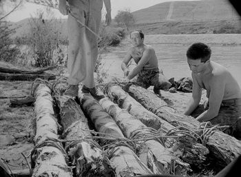 Movie still from “Fear and Desire” (1952), directed by Stanley Kubrick – A group of men standing next to a pile of logs; Wide shot, High angle