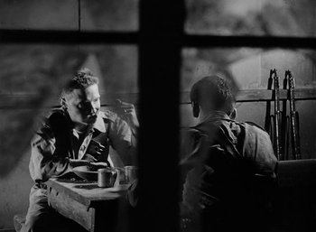 Movie still from “Fear and Desire” (1952), directed by Stanley Kubrick – Two men are sitting at a table and drinking coffee; Medium shot, Over the shoulder angle
