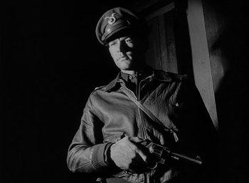 Movie still from “Fear and Desire” (1952), directed by Stanley Kubrick – A man in a military uniform holding a gun; Medium shot, Low angle