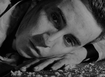 Movie still from “Fear and Desire” (1952), directed by Stanley Kubrick – Black and white photograph of a man laying on the ground; Extreme Close Up shot, Overhead angle