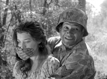 Movie still from “Fear and Desire” (1952), directed by Stanley Kubrick – A man and a woman in military fatigues covering their faces; Medium shot, Over the shoulder angle