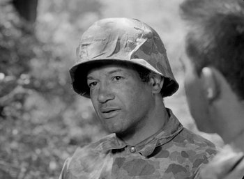 Movie still from “Fear and Desire” (1952), directed by Stanley Kubrick – Black and white photograph of a man wearing a camouflage uniform; Close Up shot, High angle