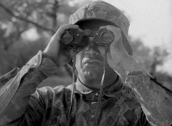 Movie still from “Fear and Desire” (1952), directed by Stanley Kubrick – A black and white photo of a man looking through binoculars; Close Up shot, Low angle