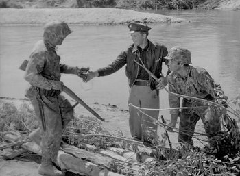 Movie still from “Fear and Desire” (1952), directed by Stanley Kubrick – A group of men standing next to a body of water; Medium shot, High angle