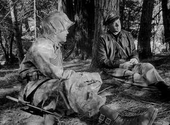 Movie still from “Fear and Desire” (1952), directed by Stanley Kubrick – Two men sitting on the ground in the woods; Medium shot, High angle