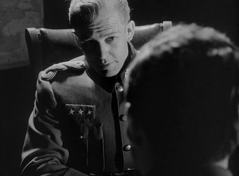 Movie still from “Fear and Desire” (1952), directed by Stanley Kubrick – A black and white photo of a man in a military uniform; Close Up shot, Over the shoulder angle