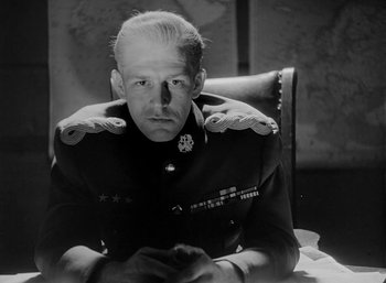 Movie still from “Fear and Desire” (1952), directed by Stanley Kubrick – A man in a military uniform sitting in a chair; Close Up shot, Low angle