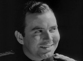 Movie still from “Fear and Desire” (1952), directed by Stanley Kubrick – Black and white photograph of a man smiling for the camera; Close Up shot, Low angle