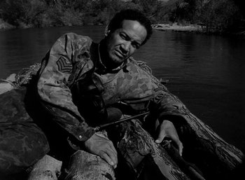 Movie still from “Fear and Desire” (1952), directed by Stanley Kubrick – Black and white photograph of a man sitting in a boat; Medium shot, High angle