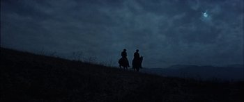 Movie still from “Flaming Star” (1960), directed by Don Siegel – Two people riding horses on a hill at night; Extreme Wide shot, Low angle