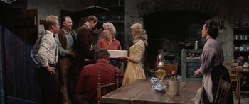 Movie still from “Flaming Star” (1960), directed by Don Siegel – A group of people standing around a table with food; Medium shot, Over the shoulder angle