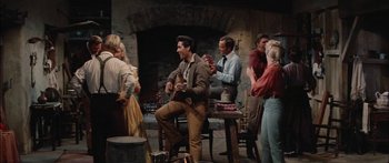 Movie still from “Flaming Star” (1960), directed by Don Siegel – A group of people standing in a living room; Wide shot, Over the shoulder angle