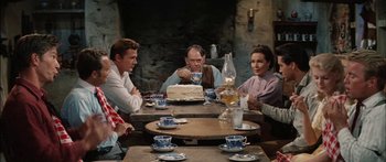 Movie still from “Flaming Star” (1960), directed by Don Siegel – A group of people sitting around a table with a cake on it; Medium shot, High angle