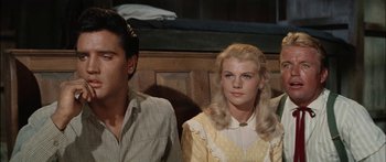 Movie still from “Flaming Star” (1960), directed by Don Siegel – A man and a woman sitting next to each other; Medium shot, Low angle