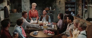 Movie still from “Flaming Star” (1960), directed by Don Siegel – A group of people sitting around a table with food; Medium shot, Over the shoulder angle