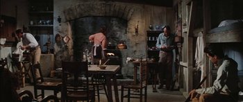 Movie still from “Flaming Star” (1960), directed by Don Siegel – Two people are cooking in an old - fashioned kitchen; Wide shot, High angle