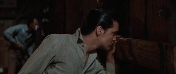 Movie still from “Flaming Star” (1960), directed by Don Siegel – A young man sitting on a couch with his hand to his face; Close Up shot, Over the shoulder angle