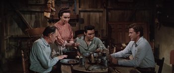 Movie still from “Flaming Star” (1960), directed by Don Siegel – A group of people sitting at a table with plates of food on it; Medium shot, High angle