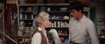 Movie still from “Flaming Star” (1960), directed by Don Siegel – A man and a woman standing next to each other in a room; Medium shot, Over the shoulder angle