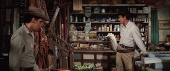 Movie still from “Flaming Star” (1960), directed by Don Siegel – A man standing in front of a counter in a store; Medium shot, Over the shoulder angle