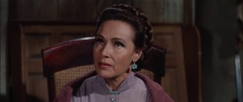 Movie still from “Flaming Star” (1960), directed by Don Siegel – An older woman wearing a purple jacket and green earrings; Close Up shot, High angle