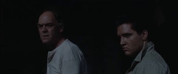 Movie still from “Flaming Star” (1960), directed by Don Siegel – Two men standing next to each other in the dark; Close Up shot, Low angle