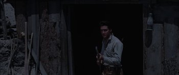 Movie still from “Flaming Star” (1960), directed by Don Siegel – A man holding an object in a dark room; Medium shot, Low angle