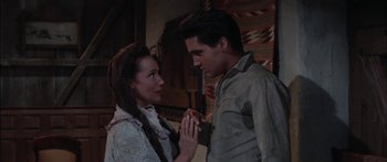 Movie still from “Flaming Star” (1960), directed by Don Siegel – A man and a woman standing next to each other; Medium shot, Over the shoulder angle