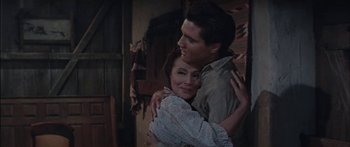 Movie still from “Flaming Star” (1960), directed by Don Siegel – A man and a woman hugging each other in a room; Medium shot, Over the shoulder angle