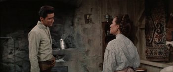 Movie still from “Flaming Star” (1960), directed by Don Siegel – A man and a woman standing next to each other in a room; Medium shot, Over the shoulder angle