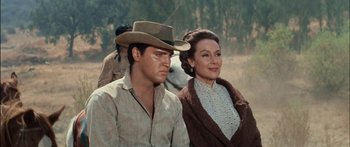 Movie still from “Flaming Star” (1960), directed by Don Siegel – A man and a woman sitting next to each other; Medium shot, Low angle