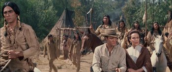 Movie still from “Flaming Star” (1960), directed by Don Siegel – A group of men in native american garb walking down a dirt road; Medium shot, Over the shoulder angle