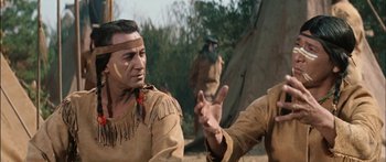 Movie still from “Flaming Star” (1960), directed by Don Siegel – Two native american men in traditional clothing talking to each other; Close Up shot, Over the shoulder angle