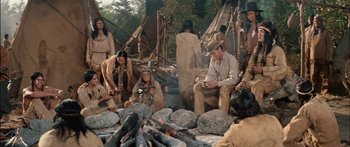 Movie still from “Flaming Star” (1960), directed by Don Siegel – A group of people sitting next to a fire pit; Wide shot, High angle