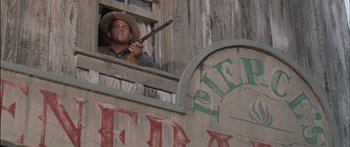 Movie still from “Flaming Star” (1960), directed by Don Siegel – A man holding a gun while looking out a window; Medium shot, Low angle