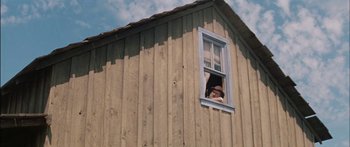 Movie still from “Flaming Star” (1960), directed by Don Siegel – A man looking out of a window of an old barn; Wide shot, Low angle