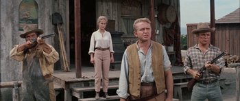 Movie still from “Flaming Star” (1960), directed by Don Siegel – A man and a woman standing on steps in front of a building; Medium shot, Low angle