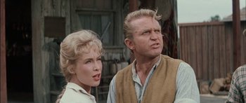 Movie still from “Flaming Star” (1960), directed by Don Siegel – A man and a woman standing next to each other; Close Up shot, Low angle