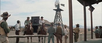 Movie still from “Flaming Star” (1960), directed by Don Siegel – A group of people standing around on horses in front of a windmill; Wide shot, Low angle
