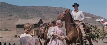 Movie still from “Flaming Star” (1960), directed by Don Siegel – A group of people riding horses on a dirt road; Medium shot, Low angle