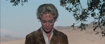 Movie still from “Flaming Star” (1960), directed by Don Siegel – A woman in a brown jacket standing next to a tree; Close Up shot, Low angle