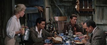 Movie still from “Flaming Star” (1960), directed by Don Siegel – A couple of men sitting at a table with food; Medium shot, Over the shoulder angle