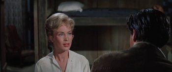 Movie still from “Flaming Star” (1960), directed by Don Siegel – A woman in a white shirt is sitting in front of a bed; Close Up shot, Over the shoulder angle
