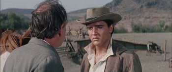 Movie still from “Flaming Star” (1960), directed by Don Siegel – A man wearing a cowboy hat talking to another man; Close Up shot, Over the shoulder angle