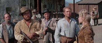 Movie still from “Flaming Star” (1960), directed by Don Siegel – A group of men standing next to each other on a street; Medium shot, Low angle