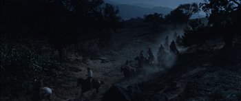 Movie still from “Flaming Star” (1960), directed by Don Siegel – A group of people riding horses down a dirt road; Extreme Wide shot, High angle